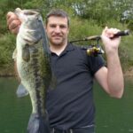 angler holding bass catch with spinning rod and reel