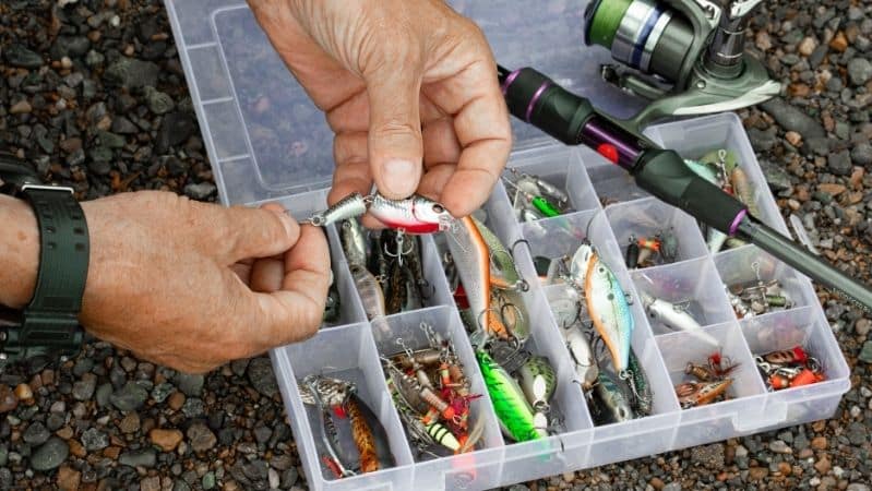 hand choosing lures from tackle box