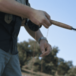 angler fixing fishing line while holding rod and reel