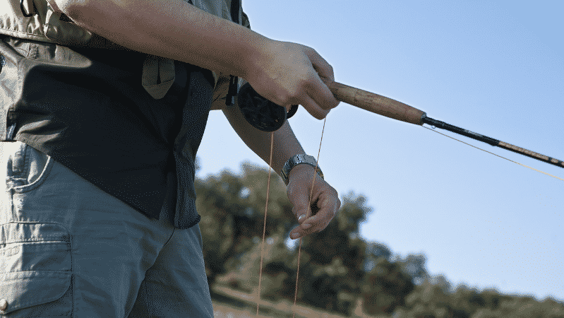 angler fixing fishing line while holding rod and reel